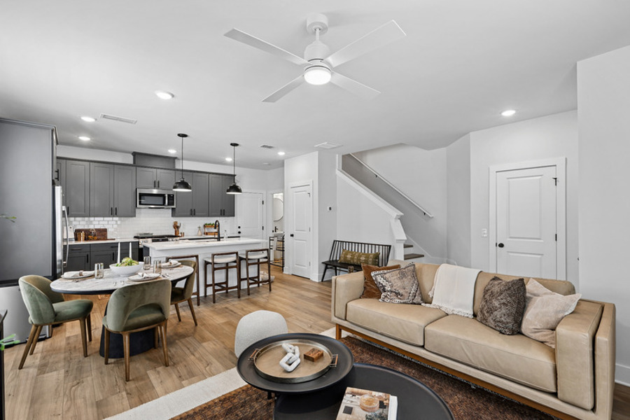 Open-concept townhome interior featuring a modern kitchen with island, dining area, and spacious living room at HARMON West Meade in Nashville, Tennessee.
