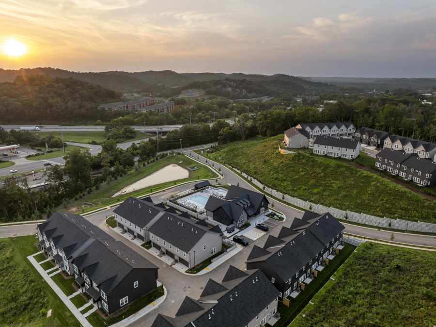 Aerial view of HARMON West Meade townhomes featuring a resort-style pool, clubhouse, and scenic hillside surroundings in Nashville, Tennessee.
