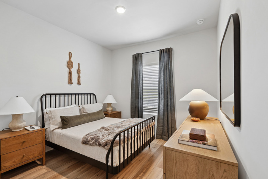 Spacious secondary bedroom with wood-style flooring, large window, and modern finishes at HARMON West Meade in Nashville, Tennessee.