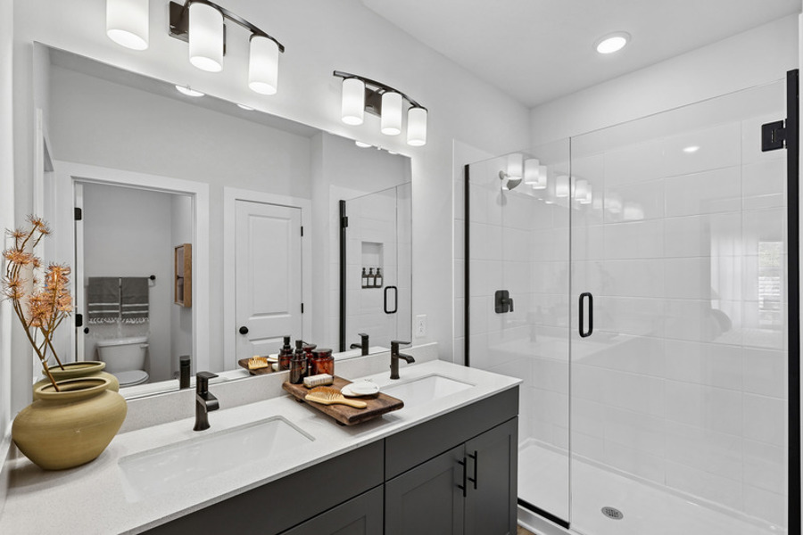 Modern bathroom with dual vanity, quartz countertops, glass-enclosed shower, and contemporary finishes at HARMON West Meade in Nashville, Tennessee.